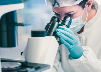 Investigadora observando a través de un microscopio en un laboratorio