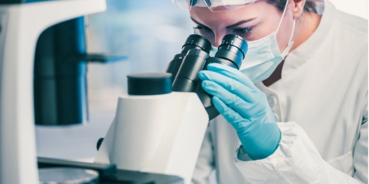 Investigadora observando a través de un microscopio en un laboratorio