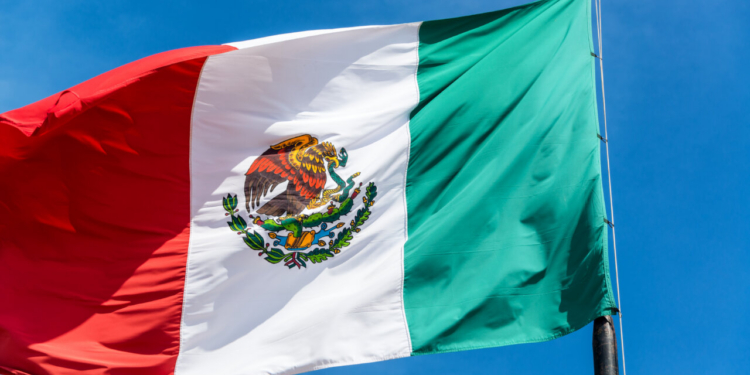 Bandera de México ondeando contra un cielo azul claro