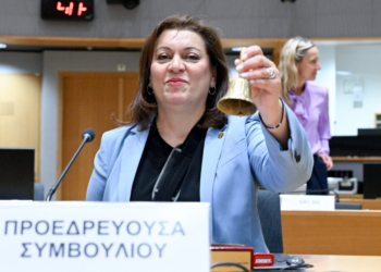 Miembro del Consejo de la Unión Europea sosteniendo una campana durante una reunión