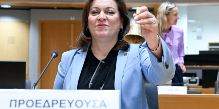 Miembro del Consejo de la Unión Europea sosteniendo una campana durante una reunión