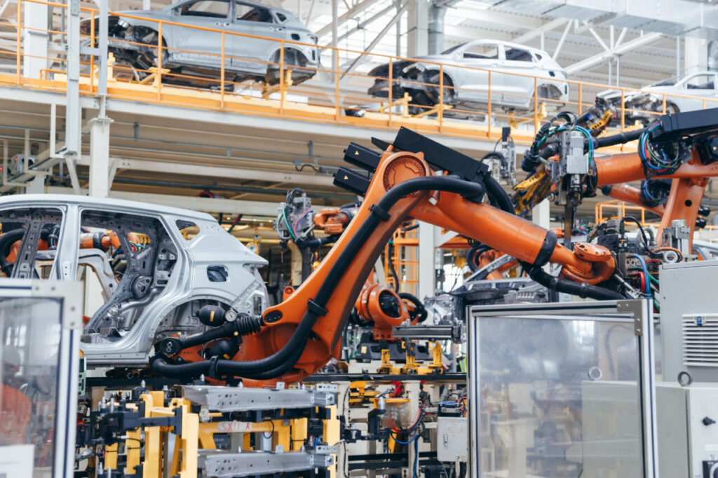 Brazos robóticos automatizados soldando estructuras de coches en una fábrica