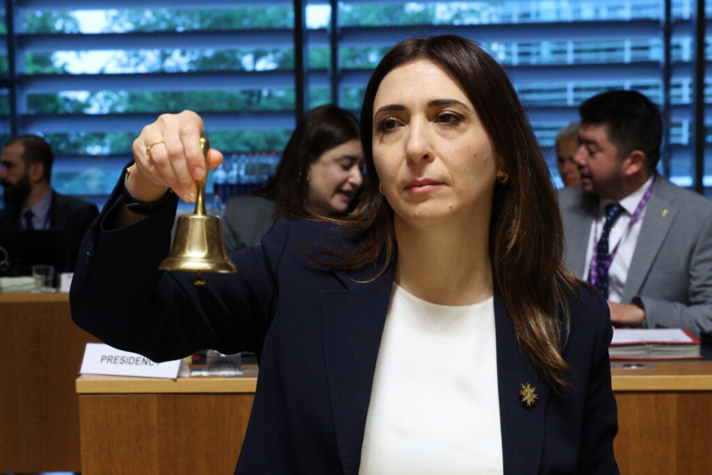 Ministra sosteniendo una campana durante la reunión del Consejo de Asuntos Generales