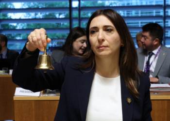 Ministra sosteniendo una campana durante la reunión del Consejo de Asuntos Generales