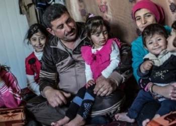Familia sentada en un ambiente acogedor, niños y adultos juntos.