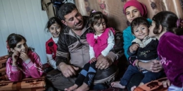 Familia sentada en un ambiente acogedor, niños y adultos juntos.