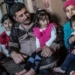 Familia sentada en un ambiente acogedor, niños y adultos juntos.