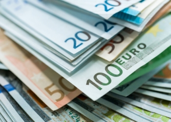 Billetes de euro y dólar apilados en un fondo