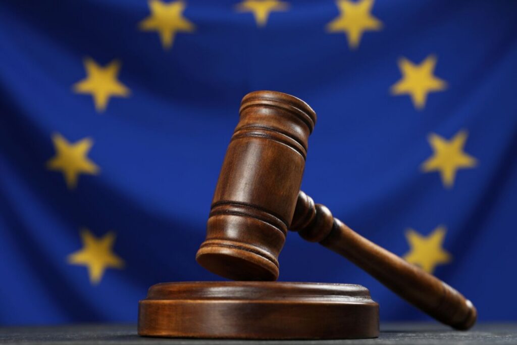 Martillo de juez sobre una mesa con la bandera de la UE de fondo