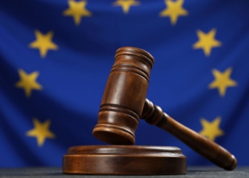 Martillo de juez sobre una mesa con la bandera de la UE de fondo