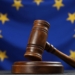 Martillo de juez sobre una mesa con la bandera de la UE de fondo