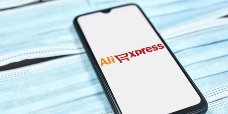 Teléfono móvil mostrando el logo de AliExpress sobre una superficie de mascarillas.