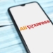 Teléfono móvil mostrando el logo de AliExpress sobre una superficie de mascarillas.