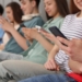 Grupo de adolescentes sentados usando smartphones en un entorno social.