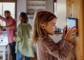 Niña interactuando con un dispositivo de control de temperatura en casa