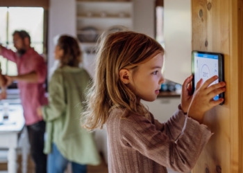 Niña interactuando con un dispositivo de control de temperatura en casa