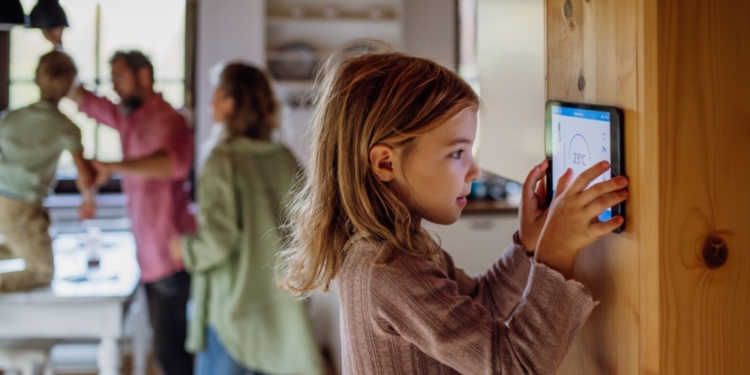 Niña interactuando con un dispositivo de control de temperatura en casa