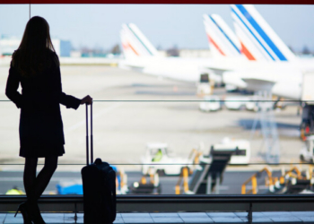 Mujer esperando en el aeropuerto con maleta de viaje