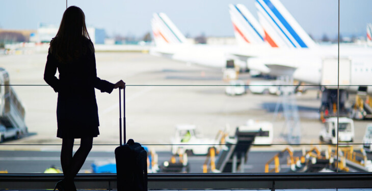 Mujer esperando en el aeropuerto con maleta de viaje