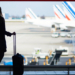 Mujer esperando en el aeropuerto con maleta de viaje