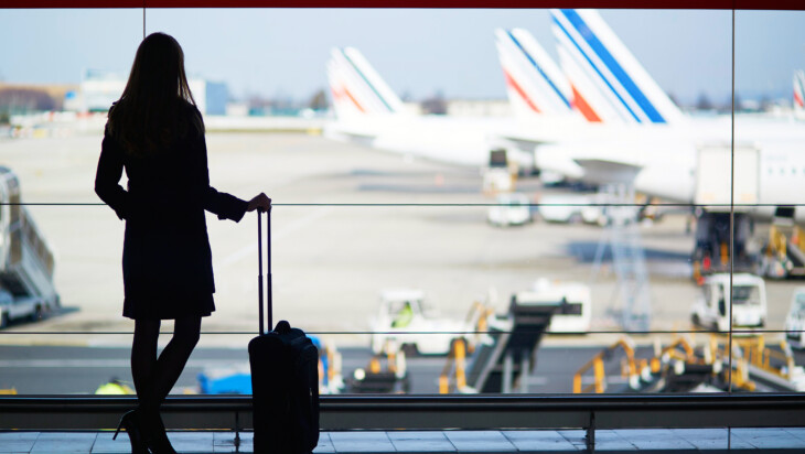 Mujer esperando en el aeropuerto con maleta de viaje